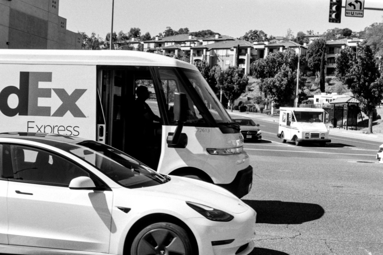 Black and white street scene with a delivery van and a modern car, illustrating vehicle delivery