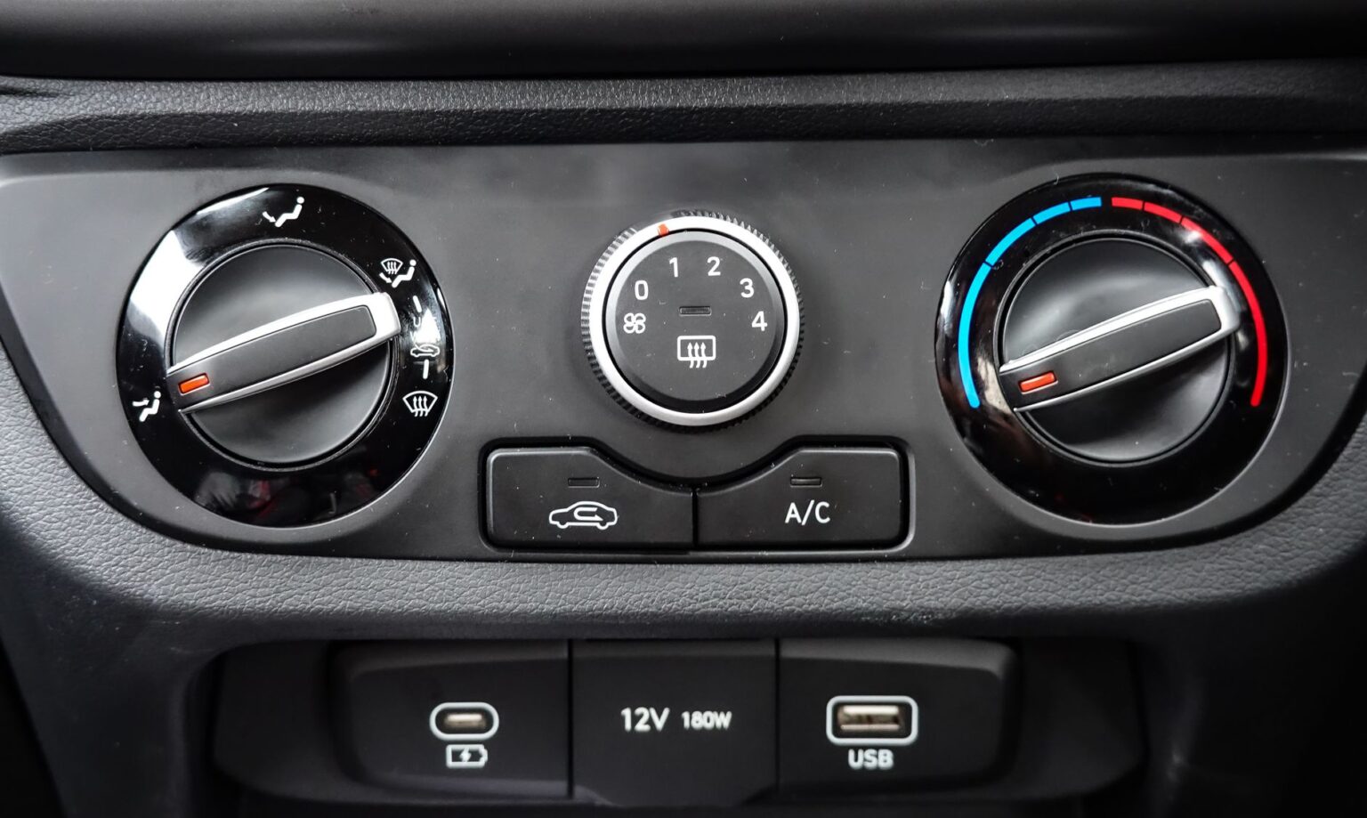 Close-up view of car air conditioning and dashboard controls, featuring climate settings and connectivity ports.