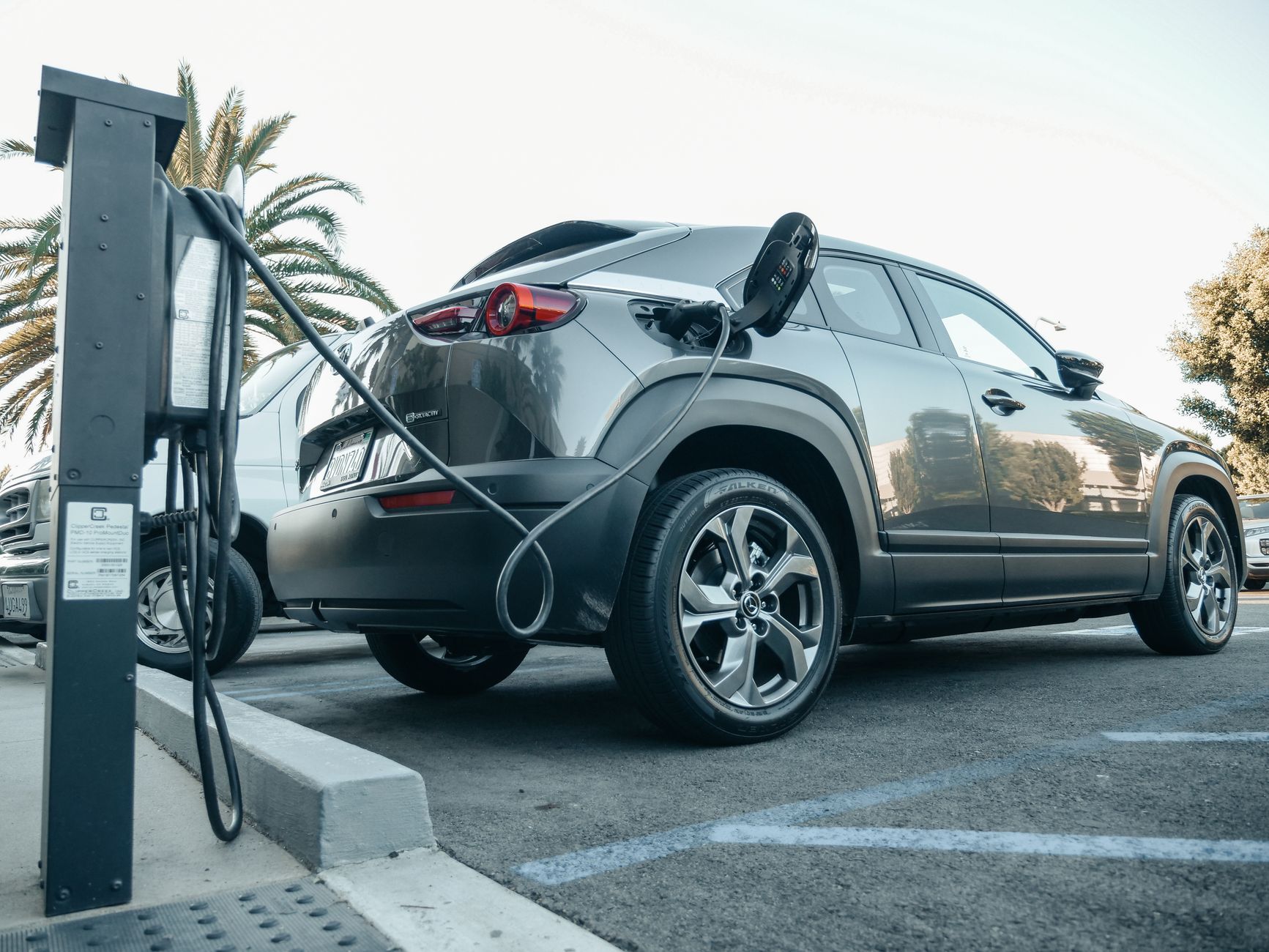 Electric vehicle plugged into a charging station in a parking lot.