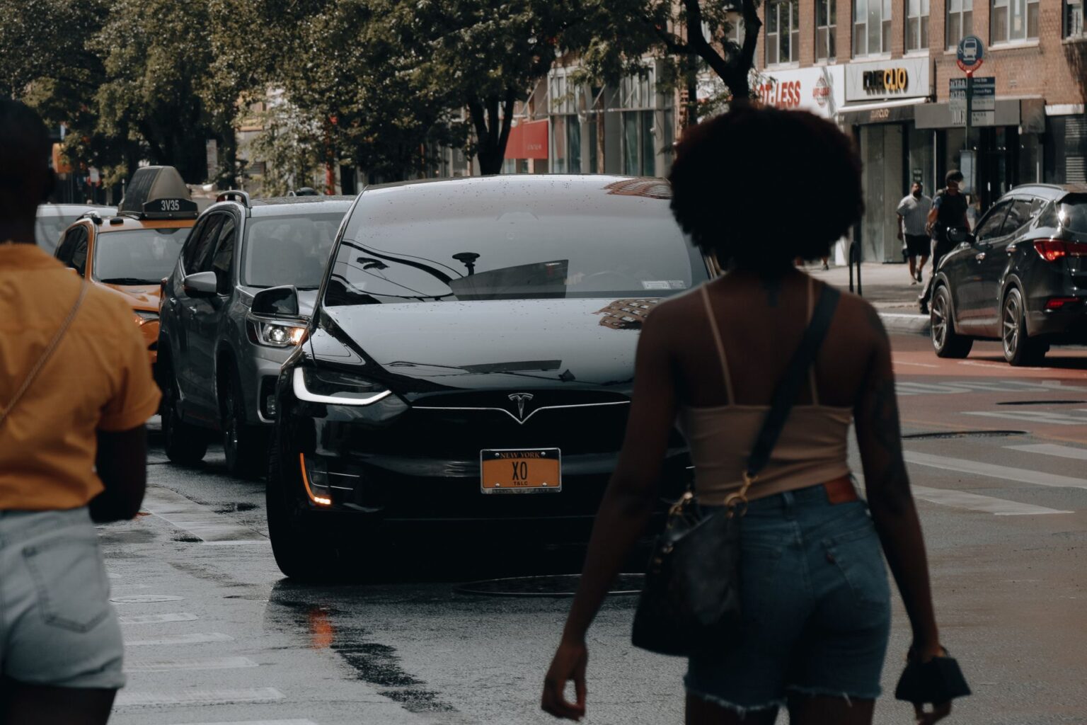 A Tesla car navigates through traffic on a busy street