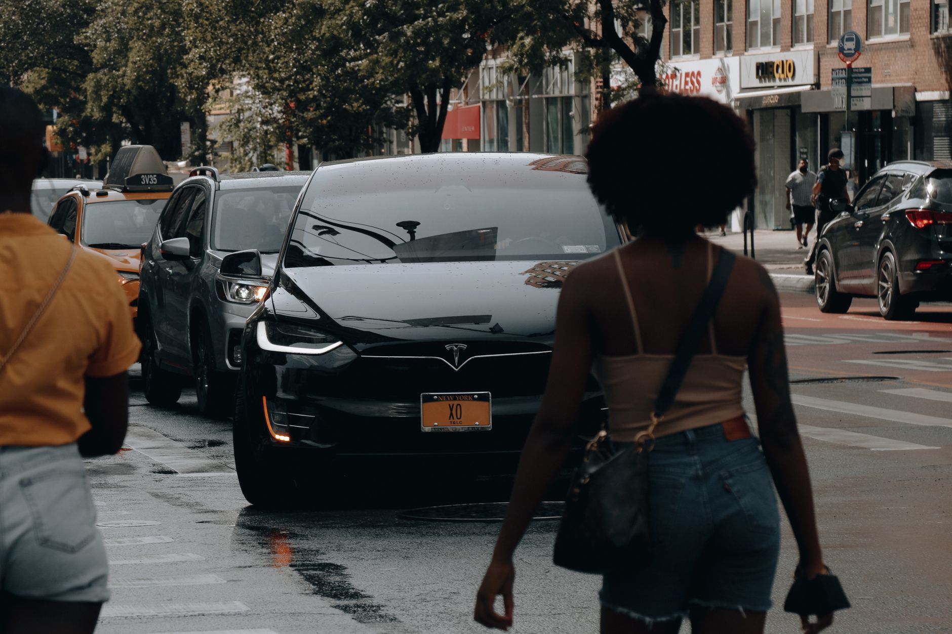 A Tesla car navigates through traffic on a busy street