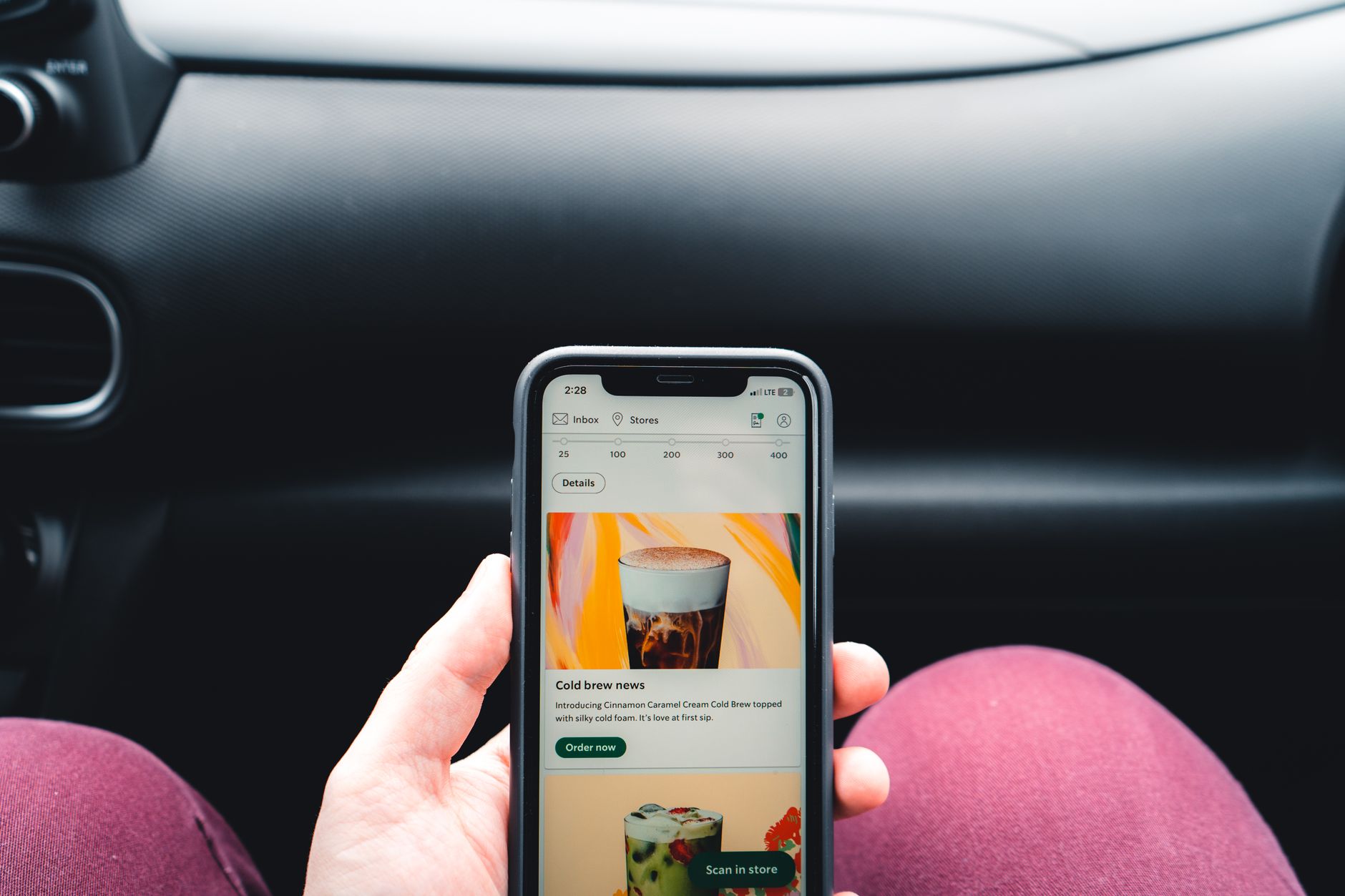 Close-up of hand holding smartphone inside a car.