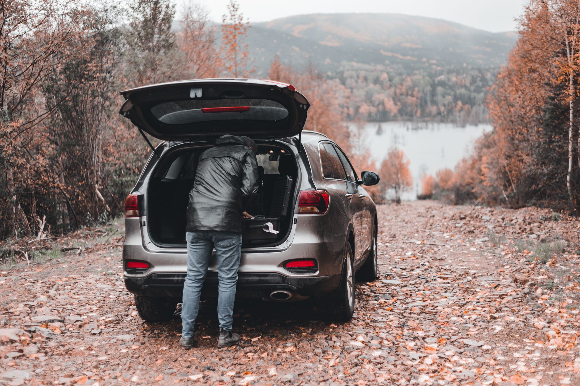 A person unloads cargo from the back of an SUV.