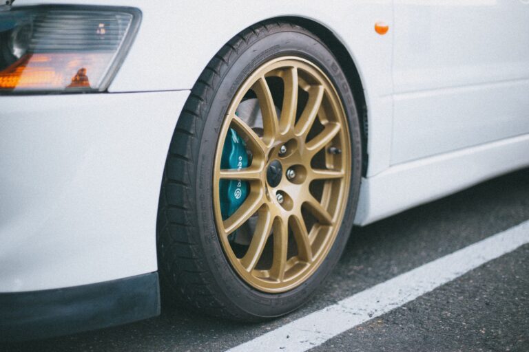 Detailed view of gold rims on a white car, showcasing automotive design.