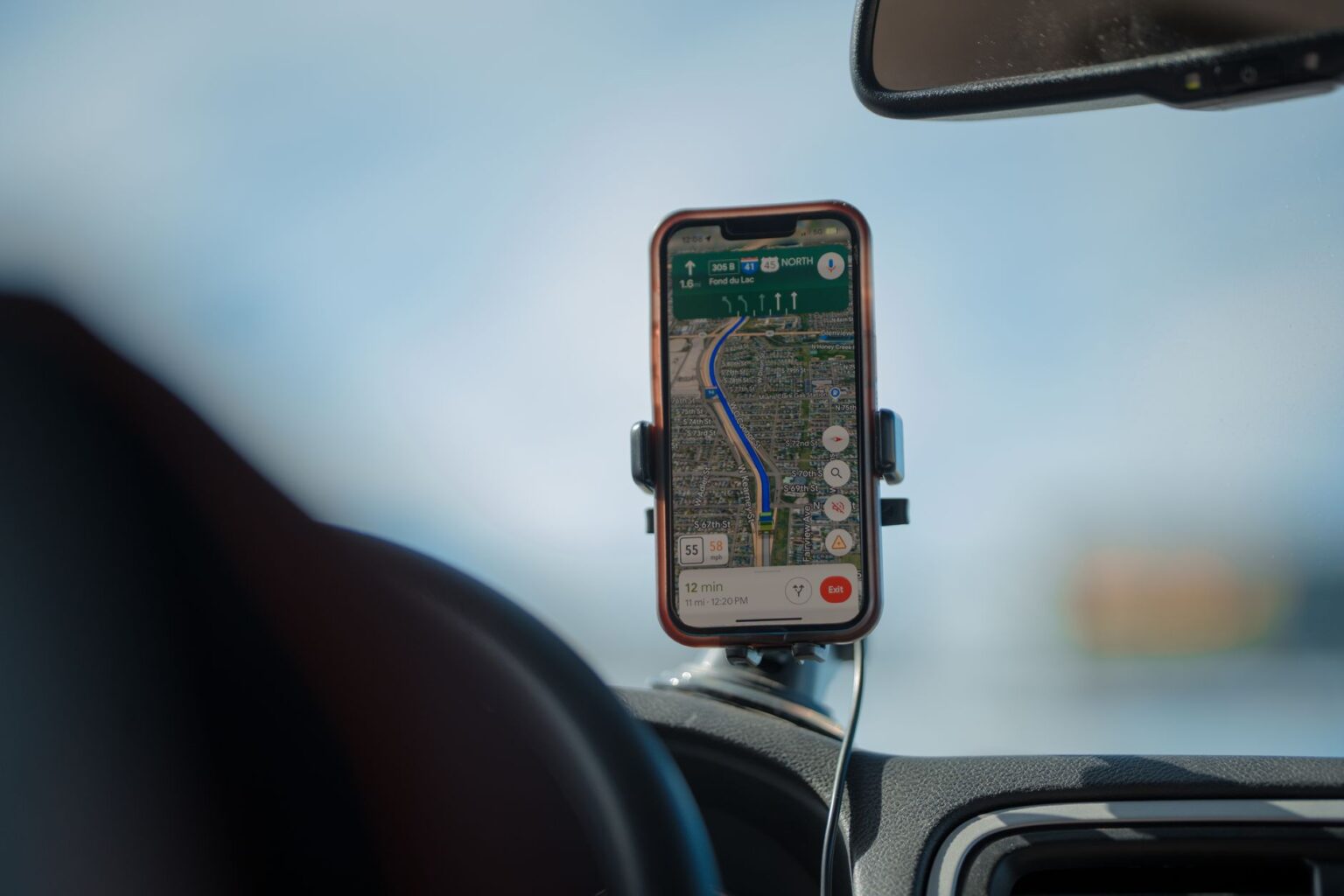 A smartphone with GPS navigation app mounted on a car dashboard during a road trip.