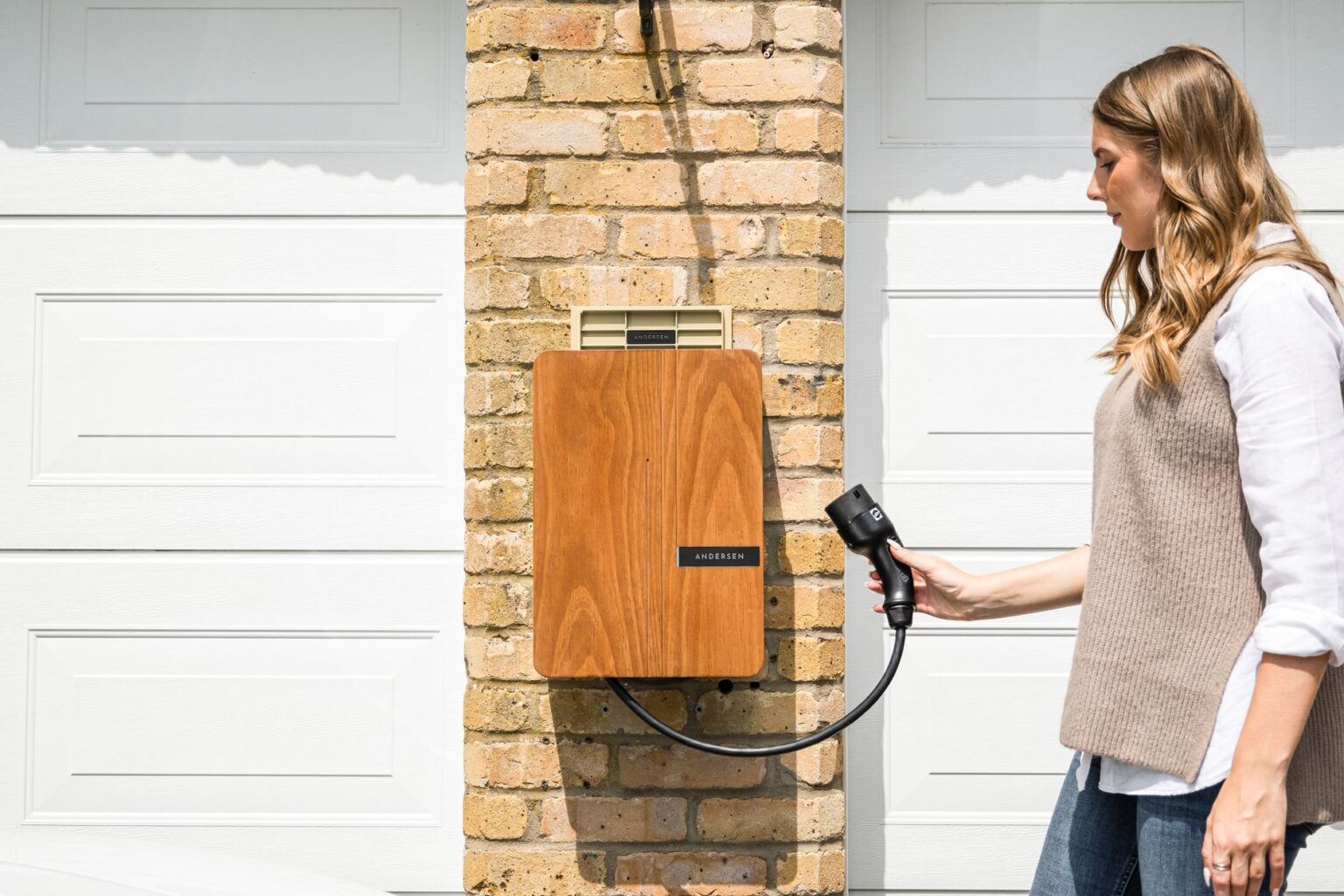 A home electric vehicle wall charger mounted on a brick wall.