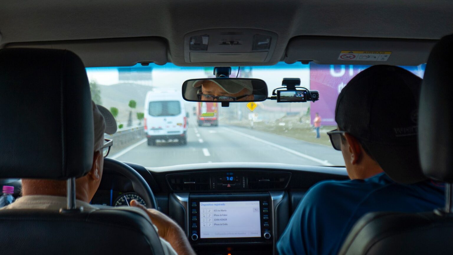 Interior of a car showing the dashboard and windshield camera area while driving