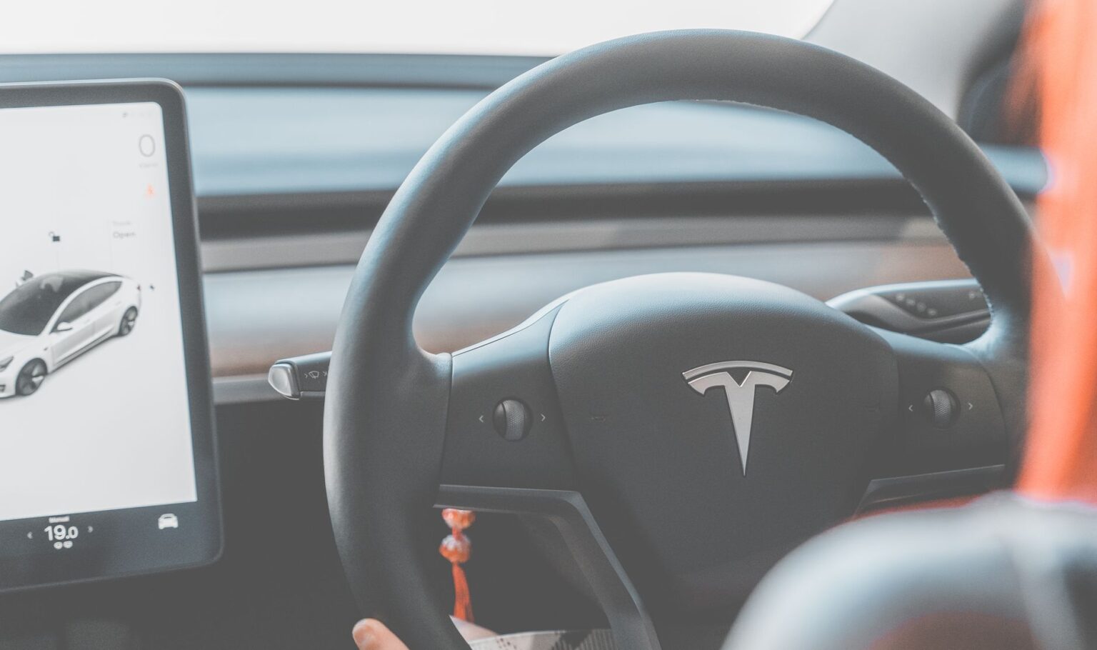 Close-up view of a Tesla electric car steering wheel and digital display, showcasing modern automotive design.