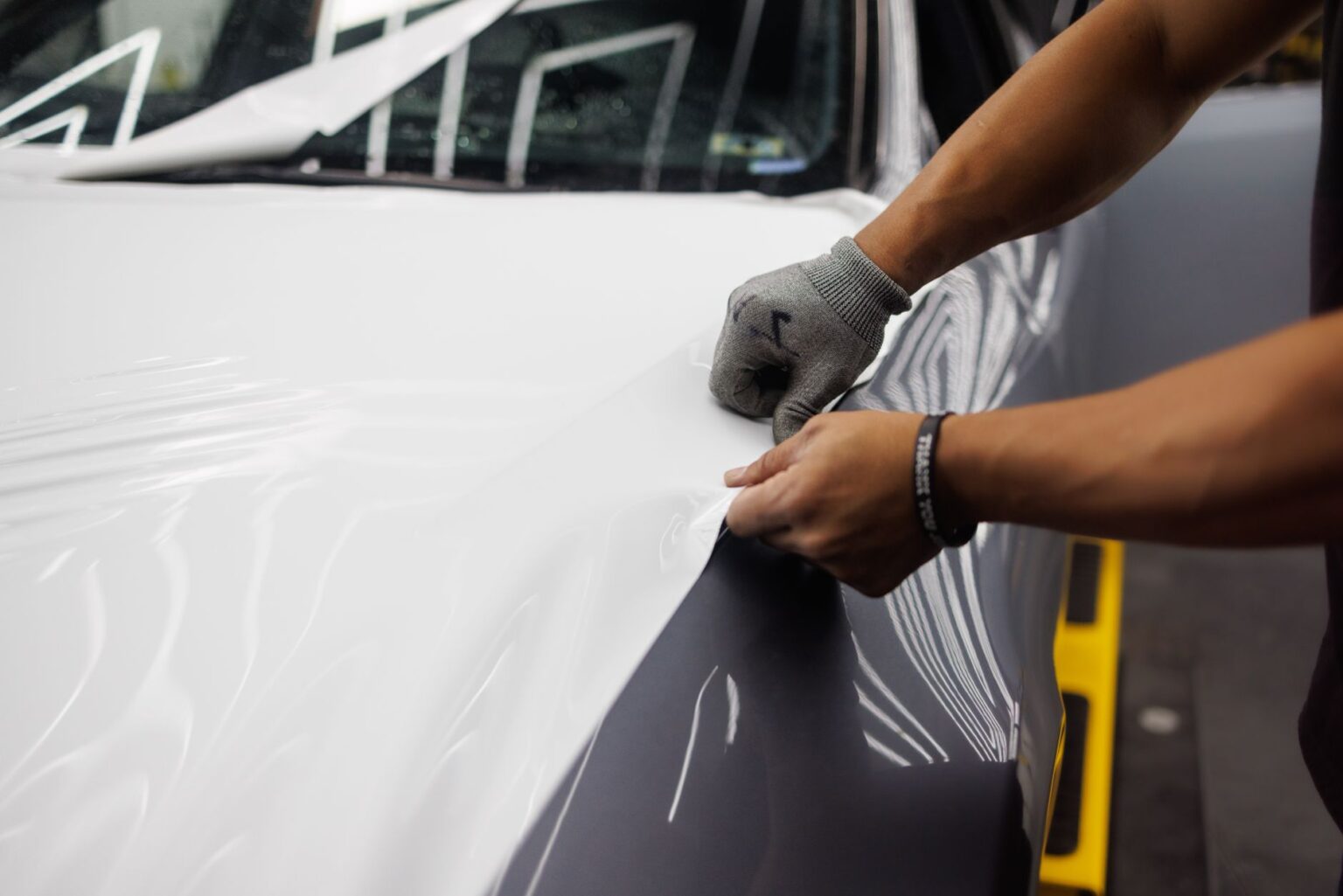 Close-up of hands applying an adhesive accessory to a car's front bumper