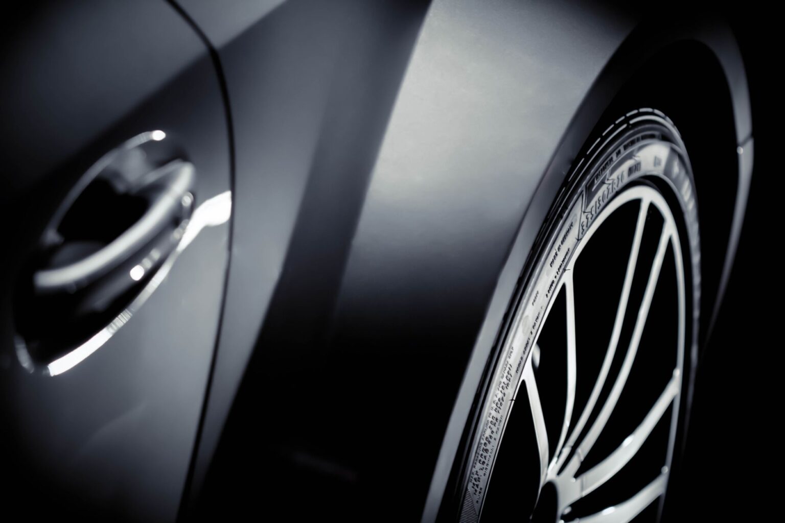 Close-up of a shiny gray car showcasing its chrome details and tire rim.