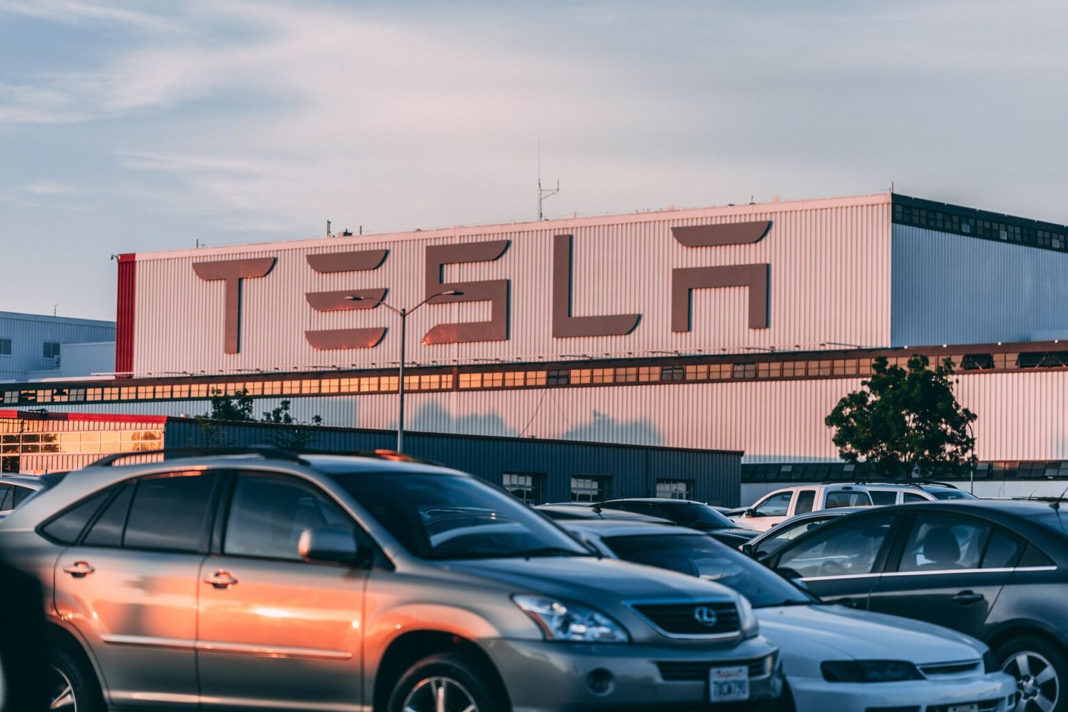 Tesla factory with parked cars during sunset